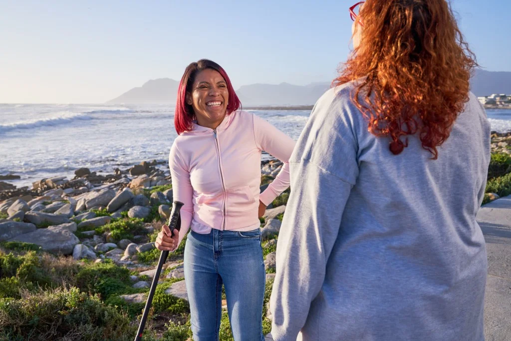 Two friends on walk by beach smiling