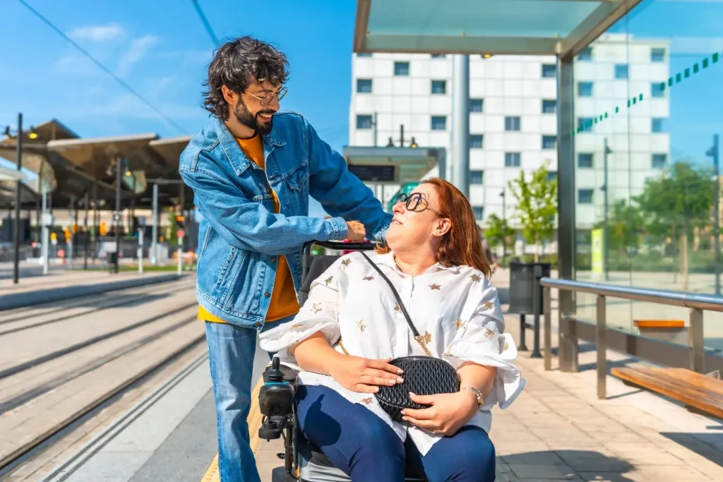 Disabled woman in wheelchair looking up at friend at train stop
